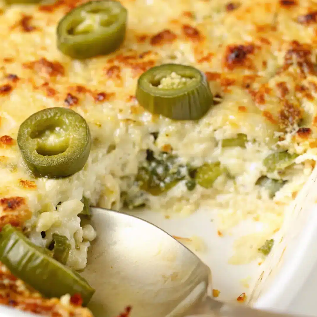 Baked Jalapeño Artichoke Dip – Creamy, Cheesy, and Spicy Baked jalapeño artichoke dip with melted cheese and sliced jalapeños in a white casserole dish