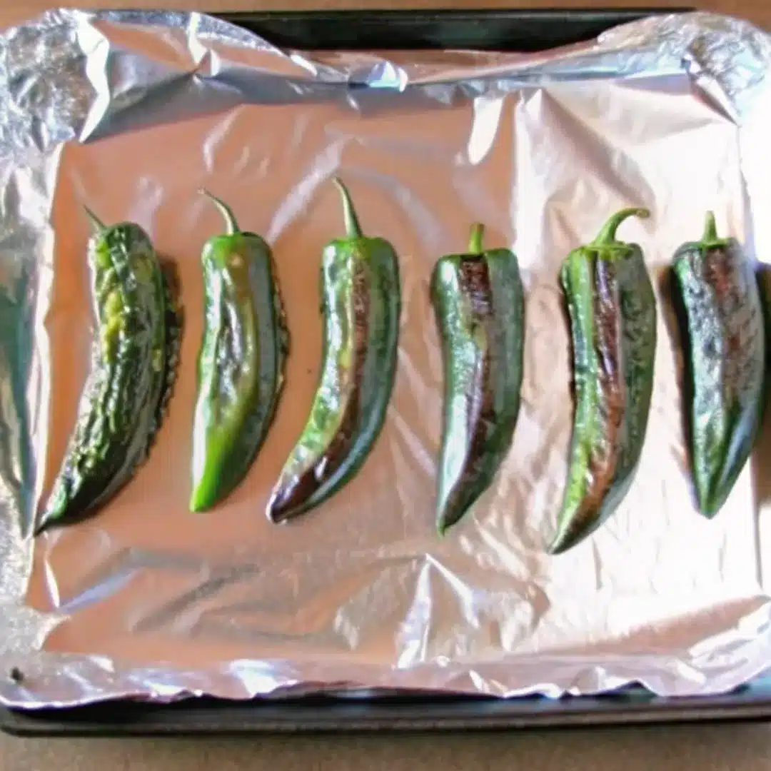Roasted Jalapeños – Smoky, Tender, and Perfectly Charred Six roasted jalapeños on a foil-lined baking sheet with blistered skin
