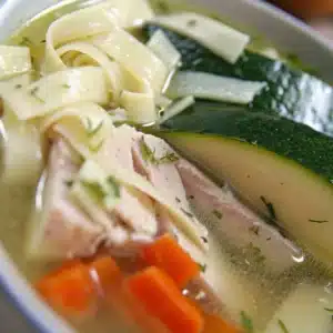 Jewish Chicken Noodle Soup Recipe: Traditional Comfort Food That Heals the Soul 19 Close-up of Jewish chicken noodle soup with sliced chicken breast, zucchini, and carrots