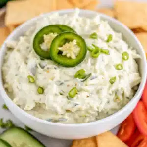 Jalapeño Artichoke Dip – The Ultimate Creamy, Spicy Party Favorite 1 creamy jalapeno artichoke dip topped with sliced peppers in a white bowl