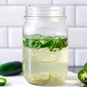 Jalapeno Simple Syrup – A Sweet & Spicy Twist You’ll Love 8 Jalapeno simple syrup in a clear mason jar with floating green slices